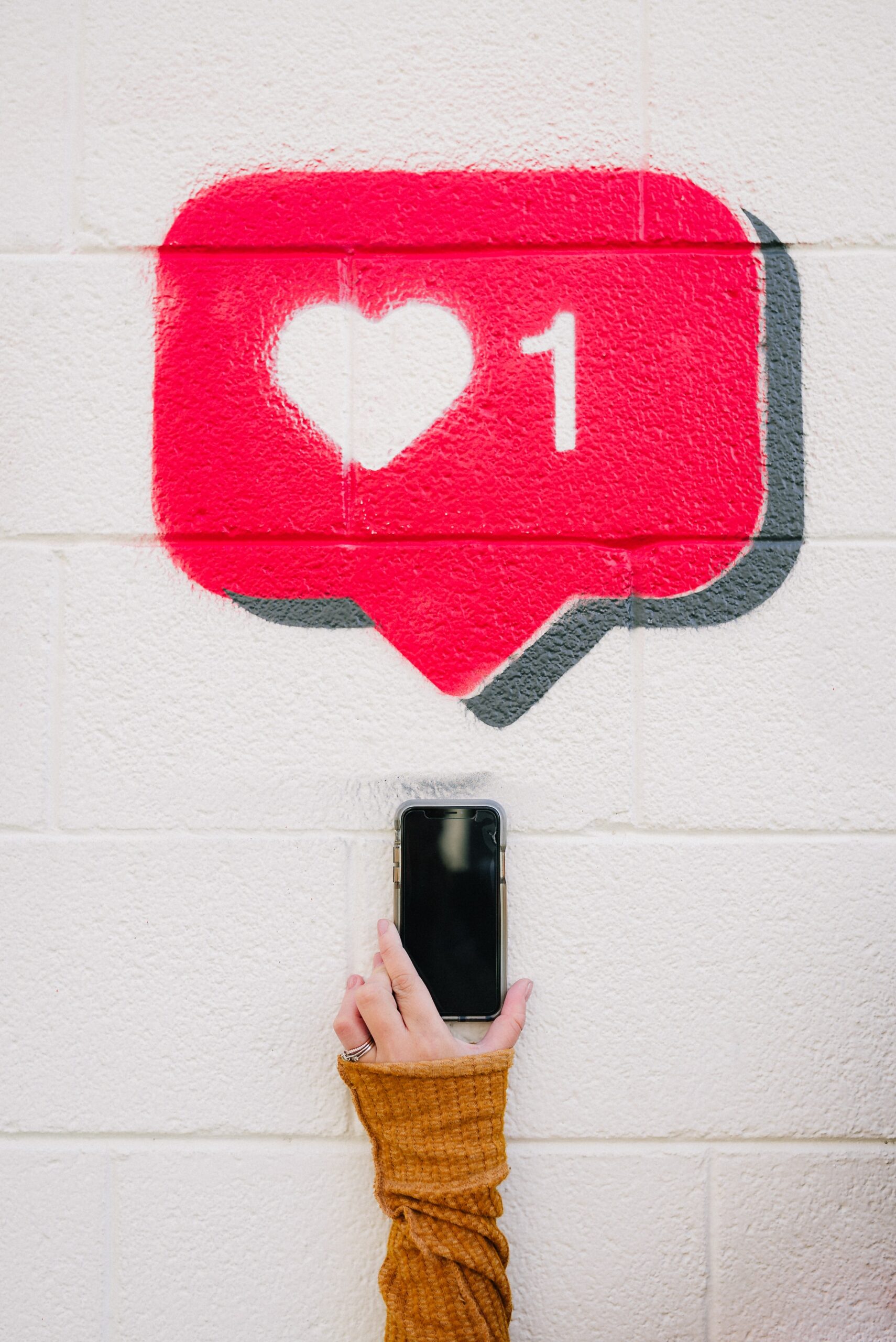 a-female-hand-is-holding-a-mobile-phone-with-a-red-pop-up-like-button-a-white-heart-on-it