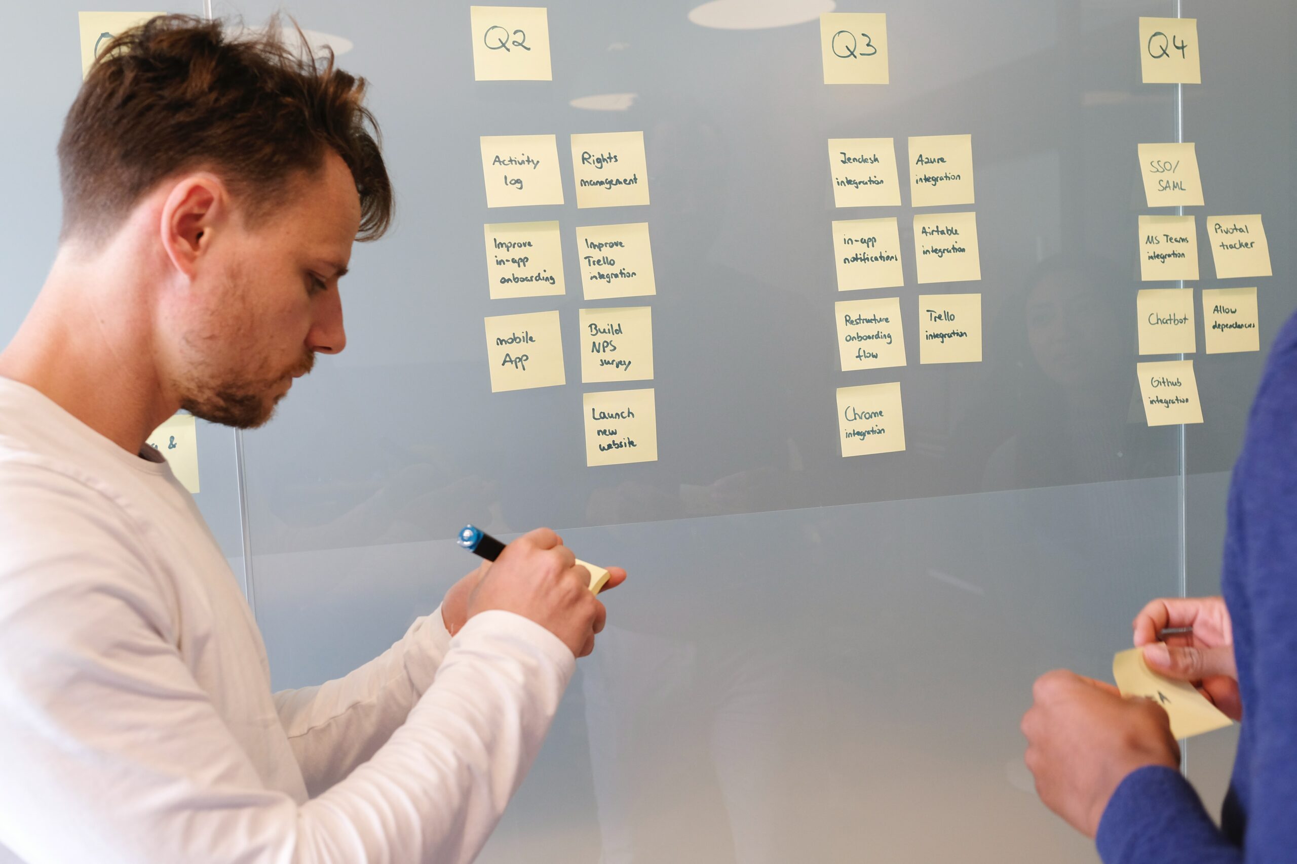 a-man-is-putting-post-its-o-the-glass-wall-as-a-process-of-product-management