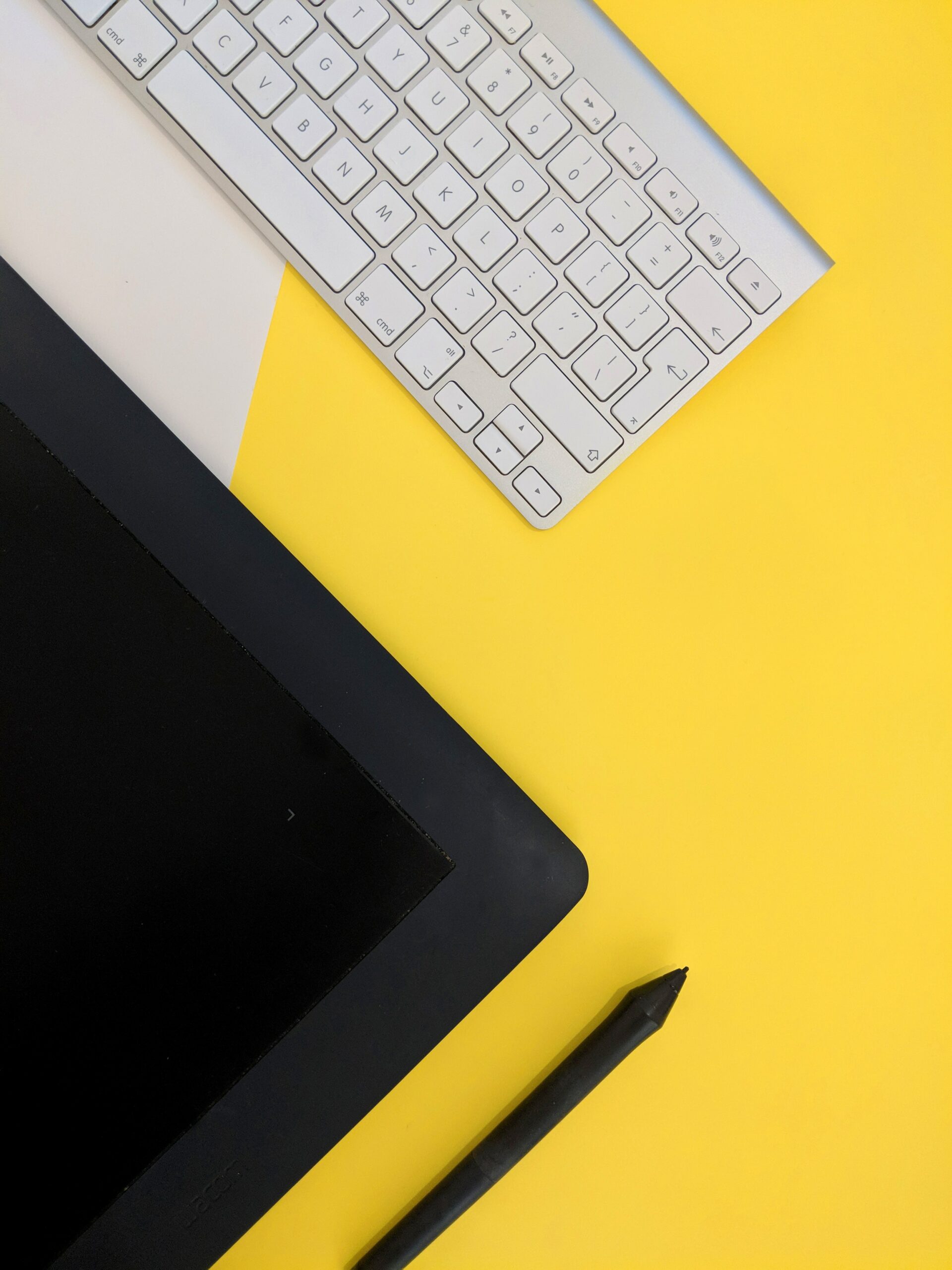 a-black-tablet-and-white-keyboard-placedon-a-yellow-table